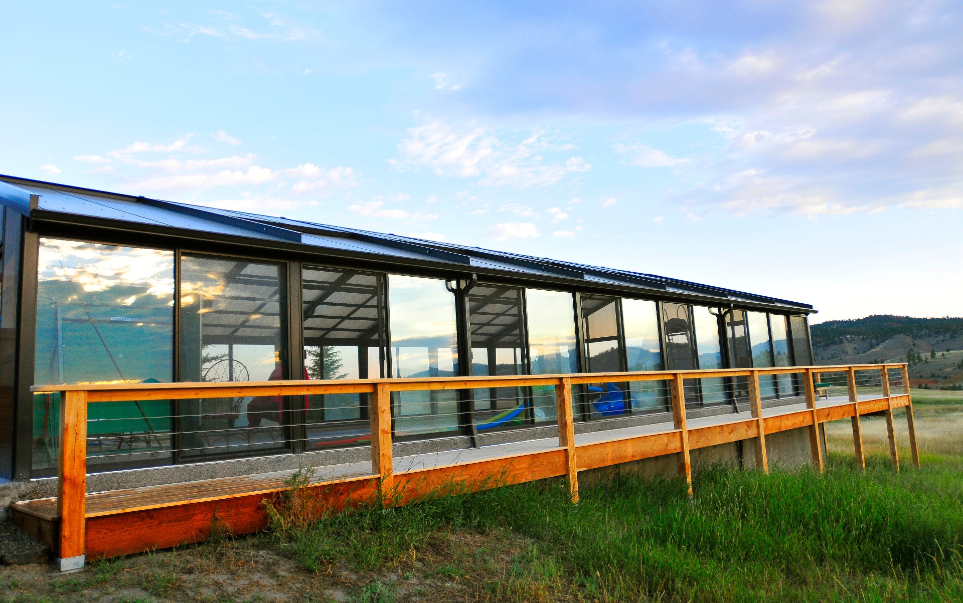 Modern glass sunroom at golden hour with mountain views